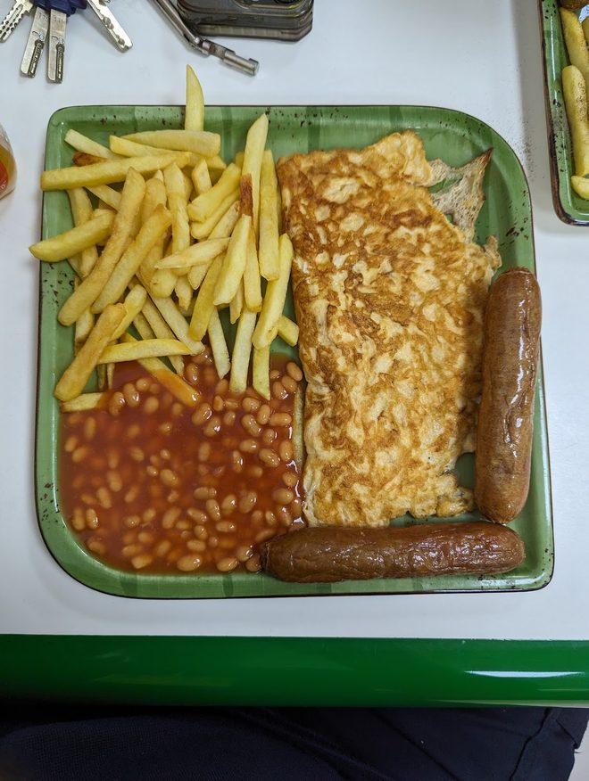 An omelette with chips and beans on a tray